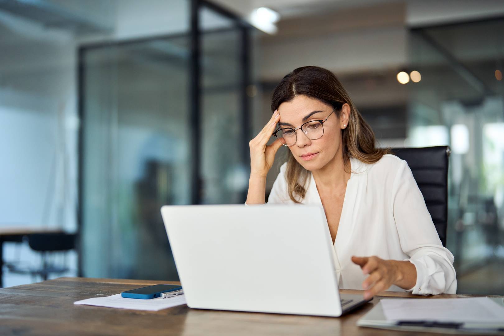 Egy hölgy gondolkodik a laptop előtt utalás előtt, mielőtt bankáártyás átverés áldozata lenne.