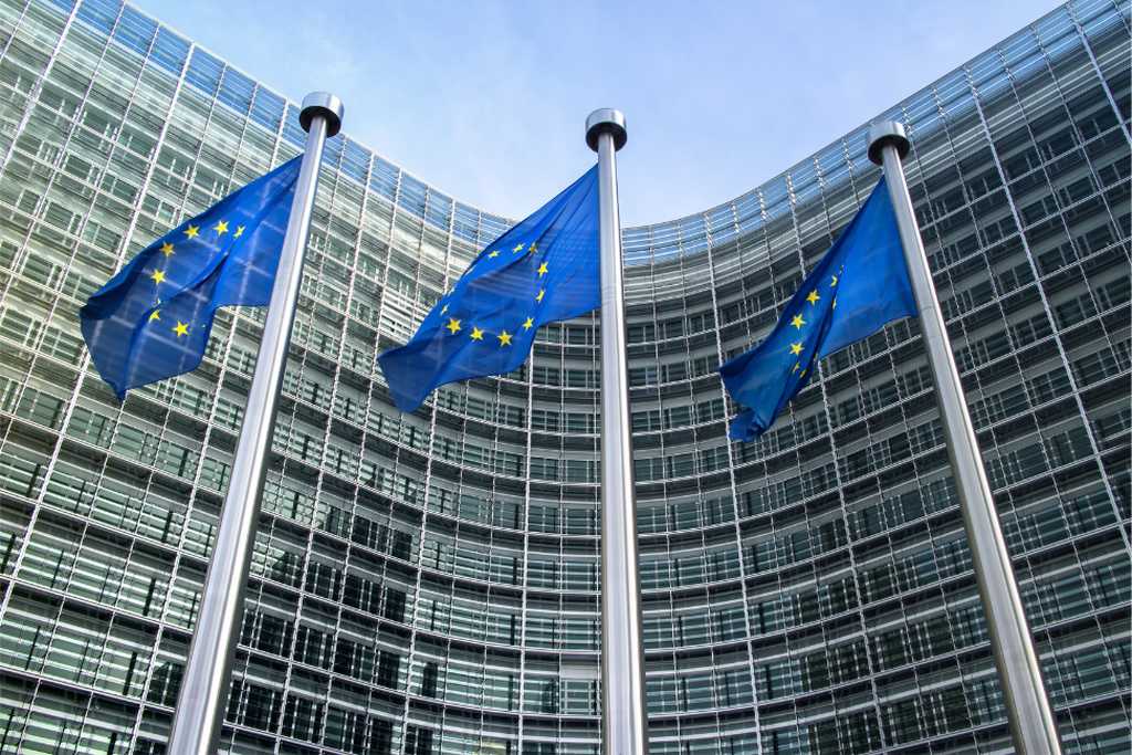 Európai Uniós zászlók háttérben az Európai Tanács épületével.